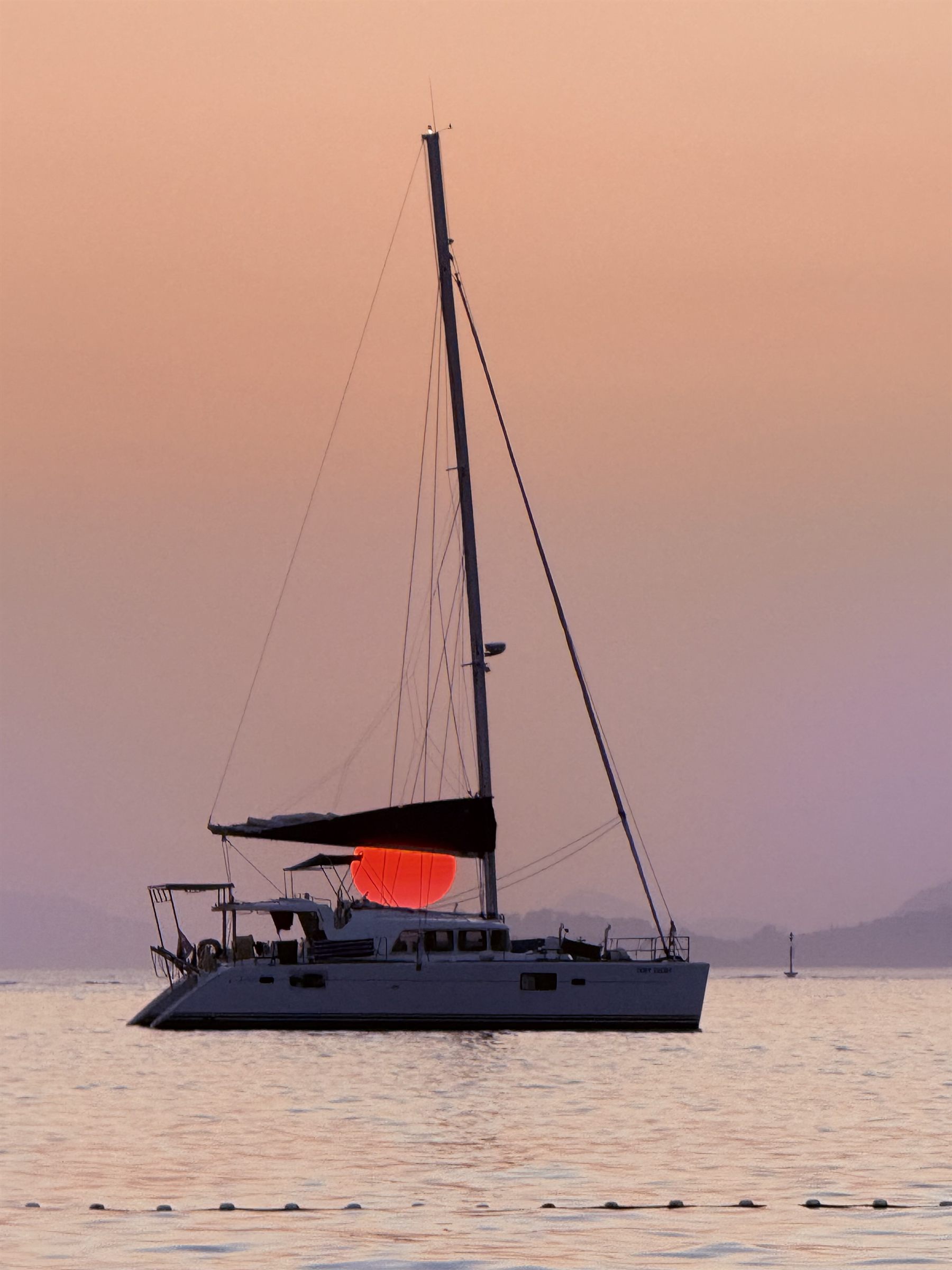 Catamaran in front of the setting sun off Cavtat